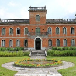 Primo piano della facciata di Villa Daziaro a Pieve Tesino. Le pareti esterne sono di color rosso mattone con scuri verdi in legno. Davanti alla villa è presente una piccola fontana tonda