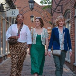 Three women, the main characters of the program, walking down an alleyway.