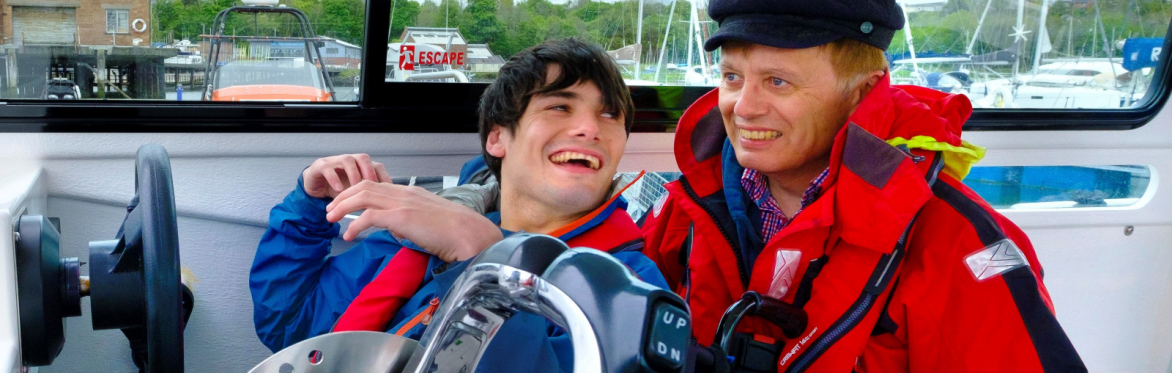 Laughing boy in wheelchair at helm of power boat