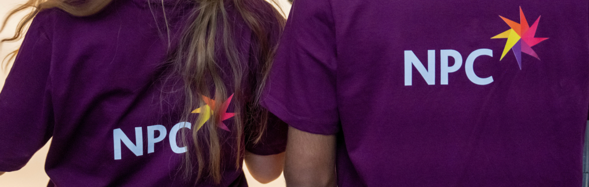 two NPC employees wearing purple t shirts that have the NPC logo on the back