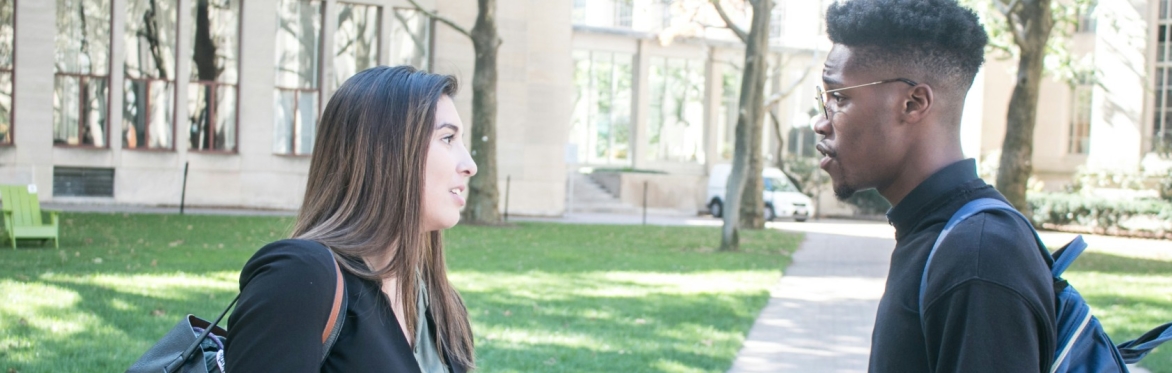 Young man and woman talking outside a school