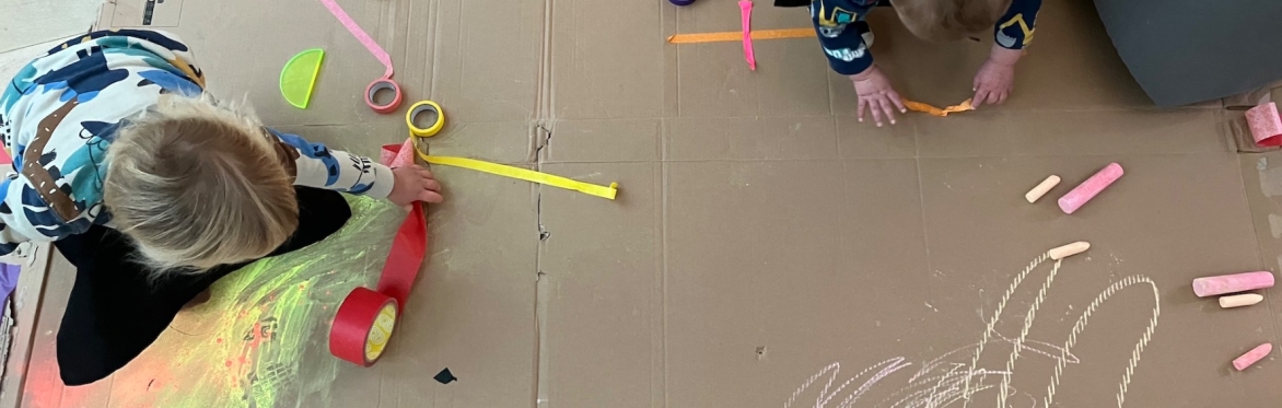 Small children drawing with chalk and playing with colourful tape