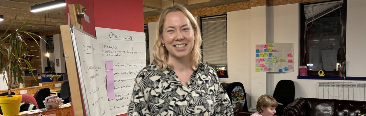 A white smiling woman stood in front of annotated flip chart paper