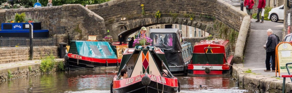 Colourful narrow boats on a river with an old stone bridge in the background