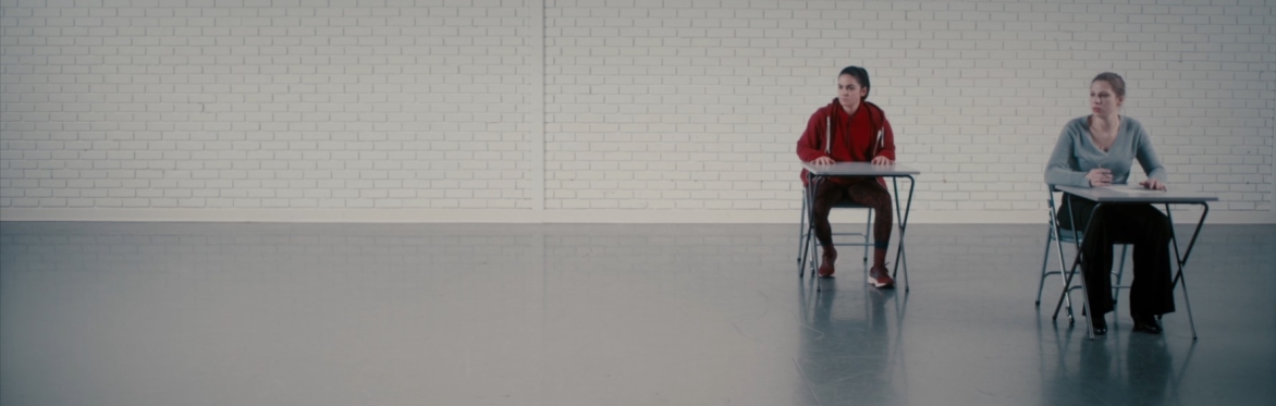 Two people sitting at desks in empty room