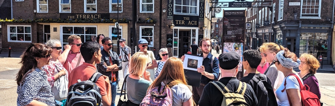 An image of a the Uncomfortable York Tour, with people listening to a guide as they talk about the history of Chocolate in the city.