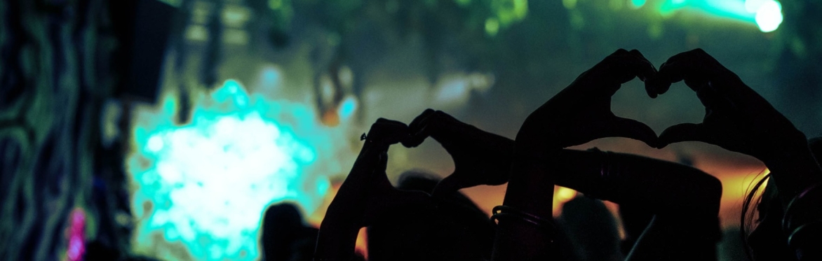 Hands making love hearts with night time festival lights in the backgrounds