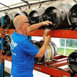 man pouring a glass of beer from a barrel