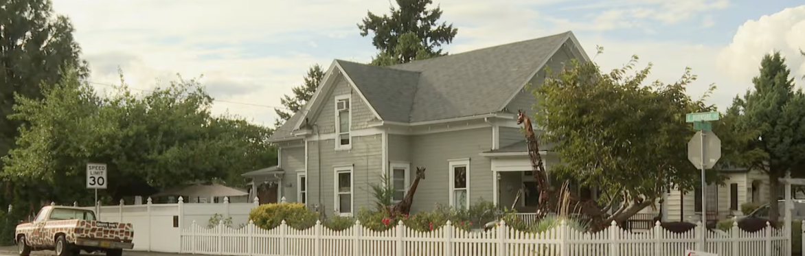 Corner lot house with giraffe sculpture in the yard