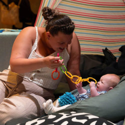 Parent and baby sitting on beanbags in an open stripey tent