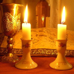 photo of lit candles, kiddush cup, and hallah cover