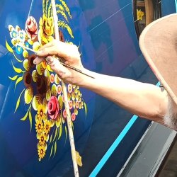 A man painting knobstick roses on a boat