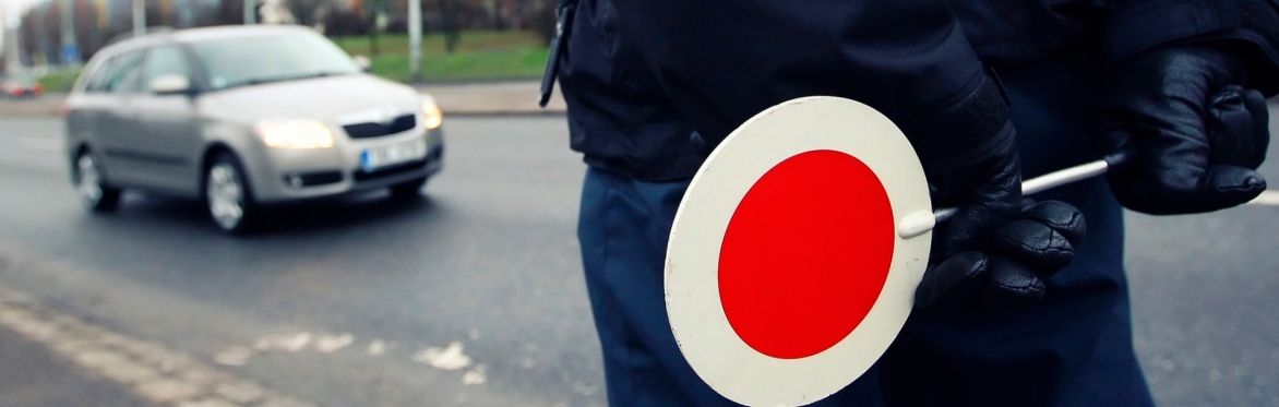 Un agente con paletta segnala l’alt a un’auto in arrivo. Un’immagine simbolo per il nostro evento ‘Guidare informati’ sulle novità del Codice della Strada