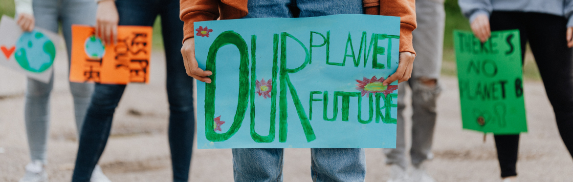 a group of young people holding signs, one in the foreground says 'Our planet, our future'