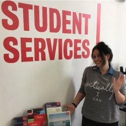 Em stands by a student service sign