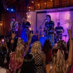 A crowd of people dressed like rock and pop stars cheering on a band on stage at the vb clubhouse stage.