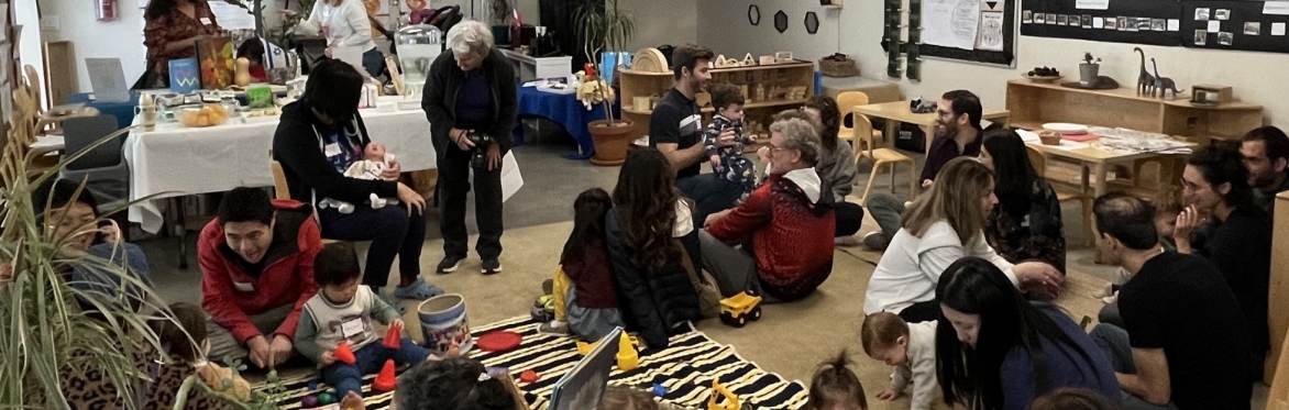 children sitting on carpet watching someone read a book