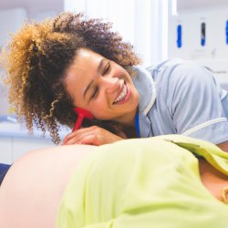 Midwife caring for a pregnant woman and listening to baby's heartbeat in a hospital room