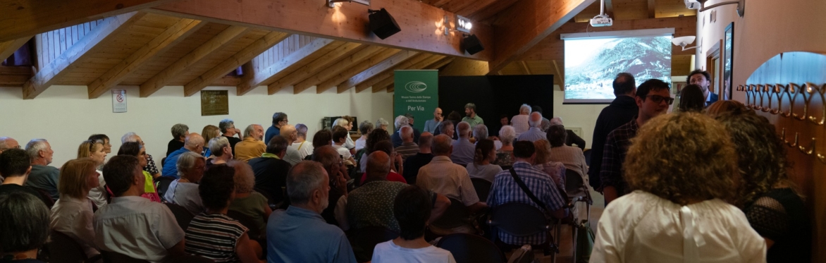 Gruppo di persone sedute che ascoltano una conferenza su Villa Daziaro. La sala è piena e ci sono diverse persone che ascoltano in piedi