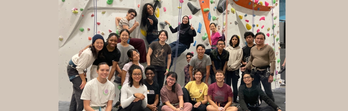 Many smiling climbers wearing harnesses indoors