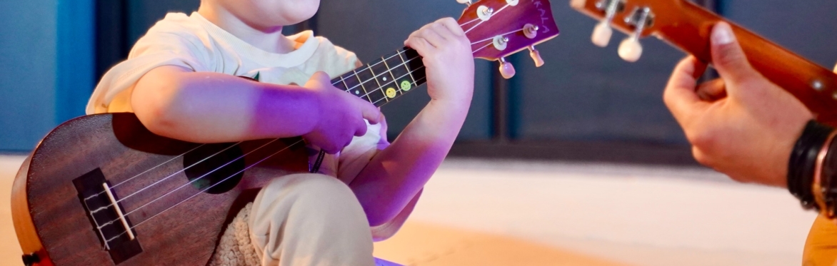 Toddler learning to play ukulele
