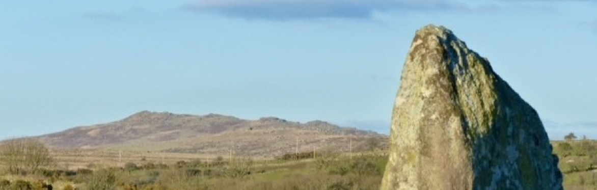 A photo of Rye Down cairn, a large stone, in front of a moorland background.