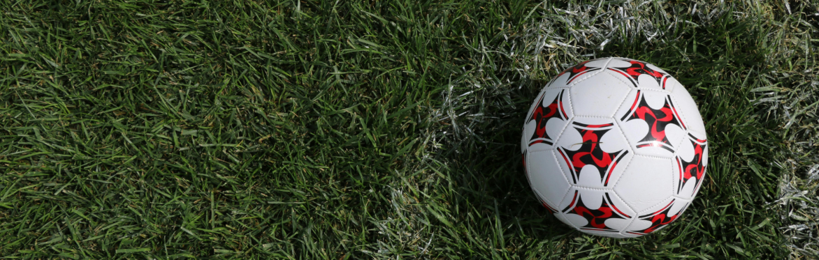 A football on a grass field near the corner flag