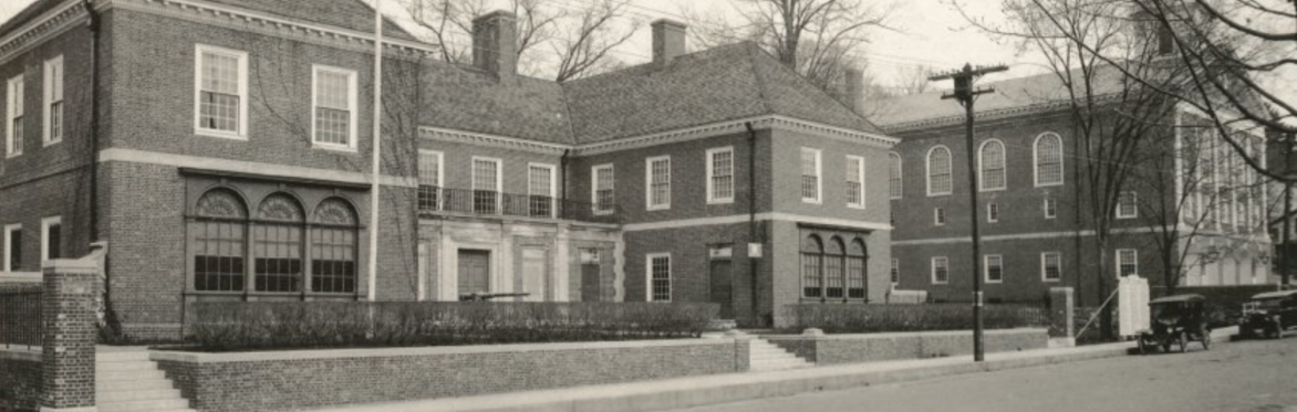 Black and white photo showing a streetscape with two large brick buildings in the Colonial Revival style.
