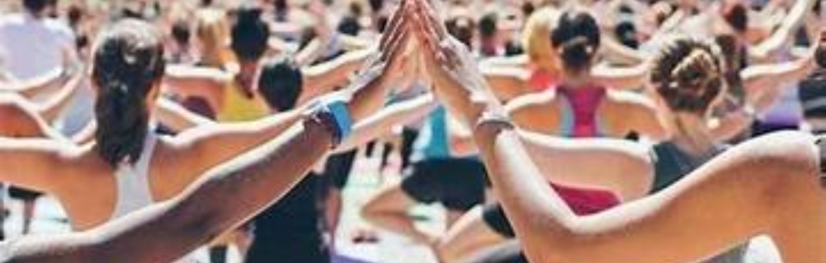 A large group of people practicing yoga with hands touching.