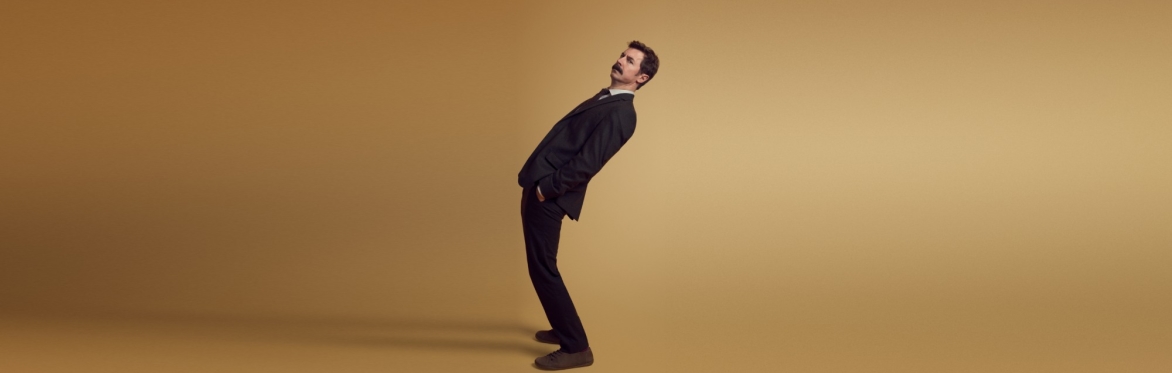 A man leaning backwards against a plain background