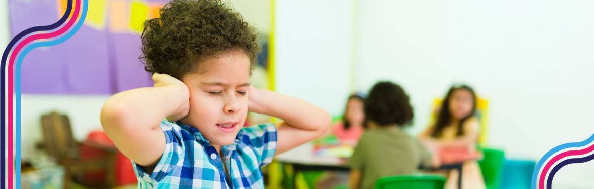 A child at school has their hands over their ears and looks distressed