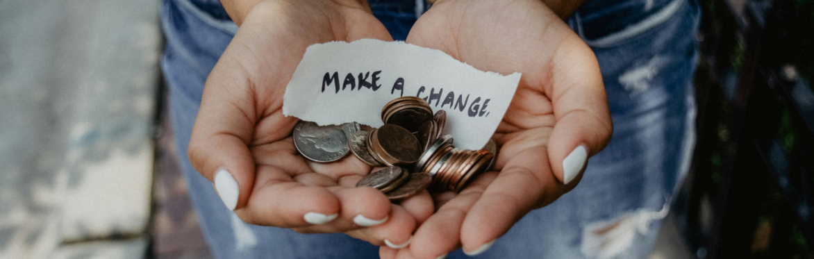 A close up of a woman cupping her hands with coins in it and a note saying make a change