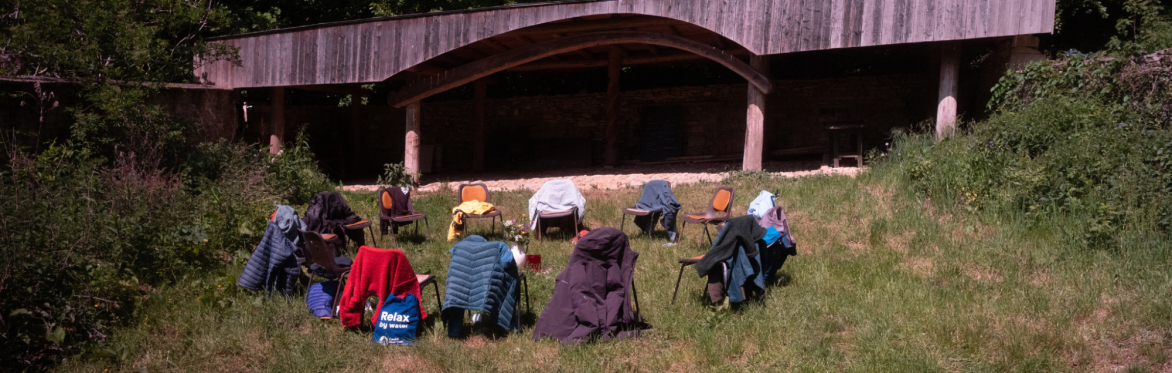 A circle of chairs in a field with people's belongings on in the sunshine