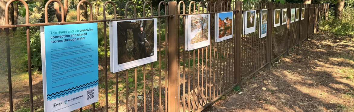 Exhibition featuring portraits and stories displayed along a park railings, exploring connections between people, rivers and place.