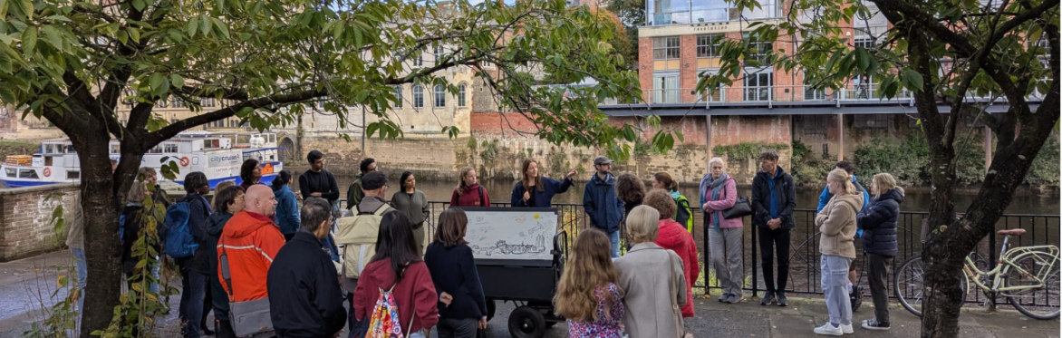 Group gathered beside the River Ouse at North Street Gardens, taking part in a guided York rivers trail discussion and creative engagement activity.