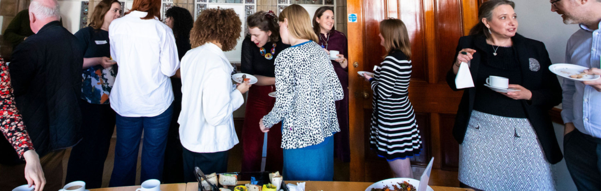 A group of fundraisers are chatting to each other while drinking coffee in small groups