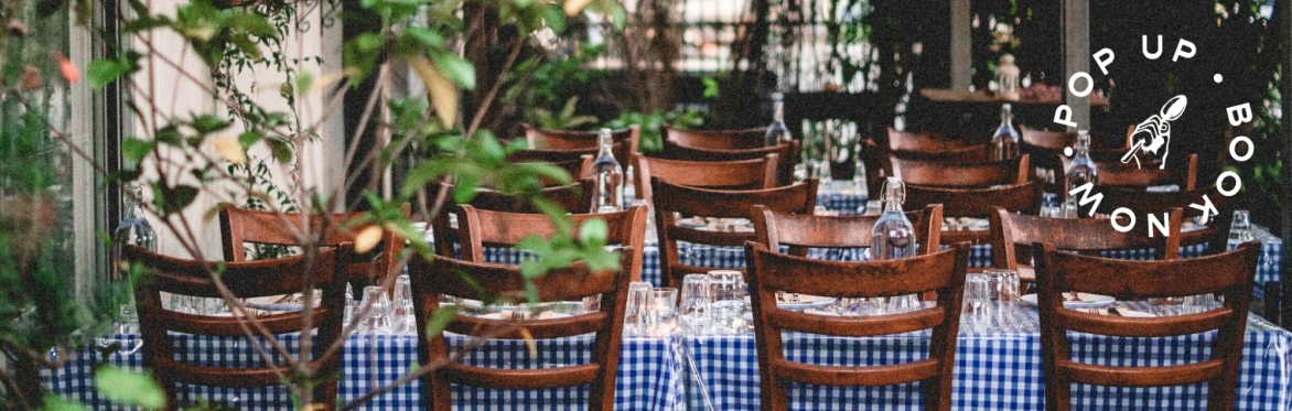 image of greek taverna setting with wooden chairs, and tables with the classic greek blue and white gingham tablecloths