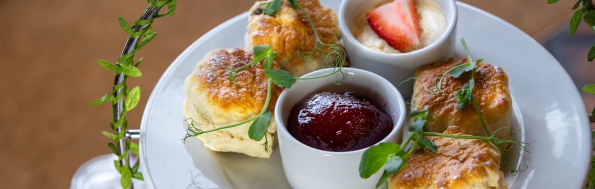 Scones, strawberry jam and cream on the top of an afternoon tea stand.