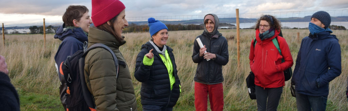 Smiling people dressed warmly and gathered in a group in the fields of Lauriston Farm