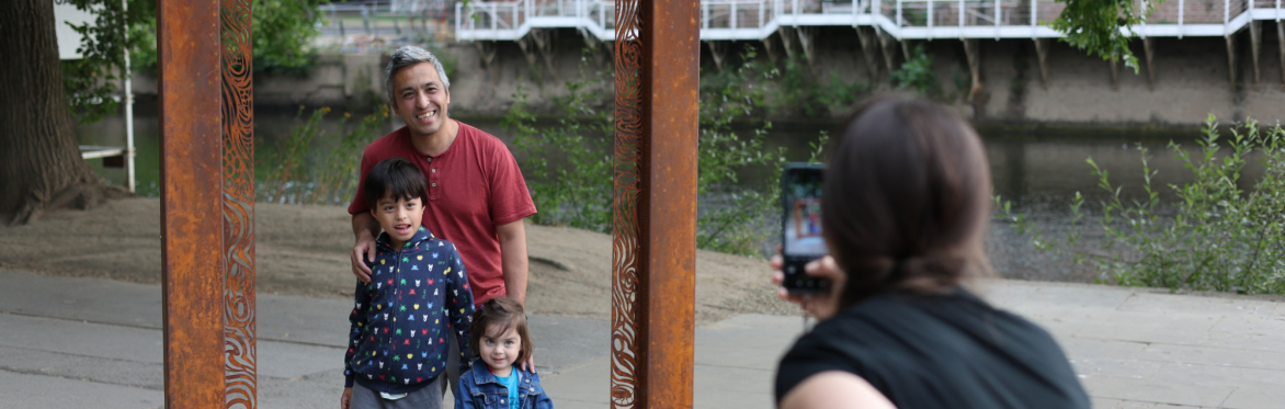 Family posing within a York rivers trail heritage frame beside the river, creating a shared moment of exploration and creativity.