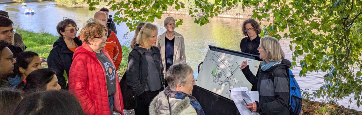 Group gathered beside the river around an illustrated map during a discussion about rivers, communities and environmental resilience.