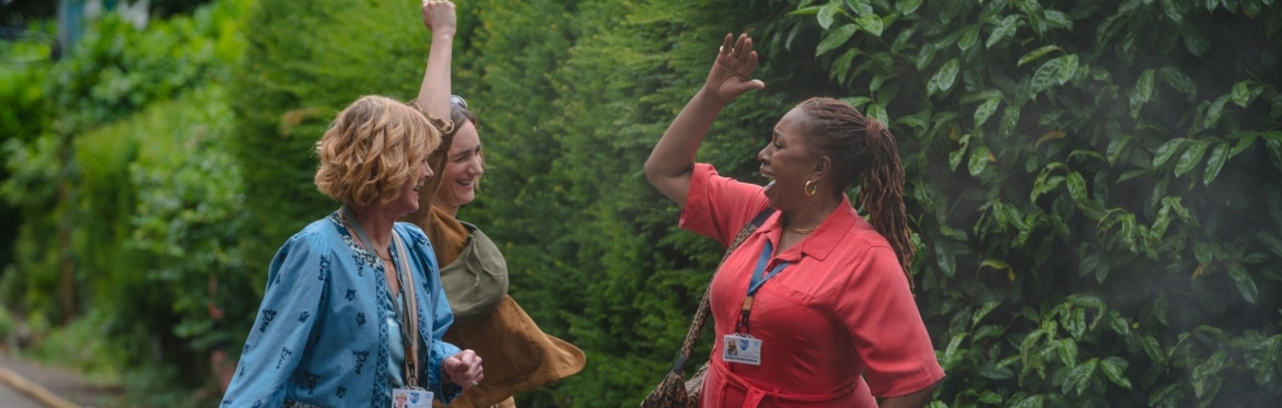 Three women, the main characters of the program, cheering with their hands in the air.