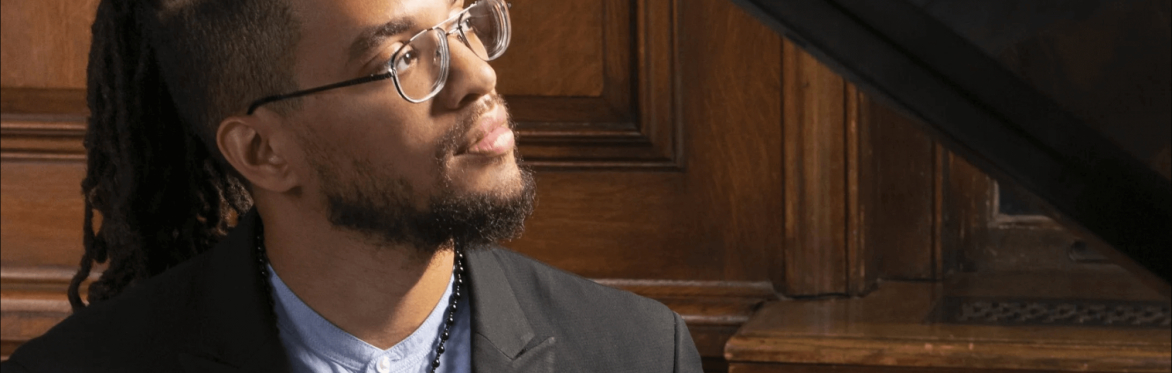 Portrait of Joshua Jenkins sitting at a grand piano