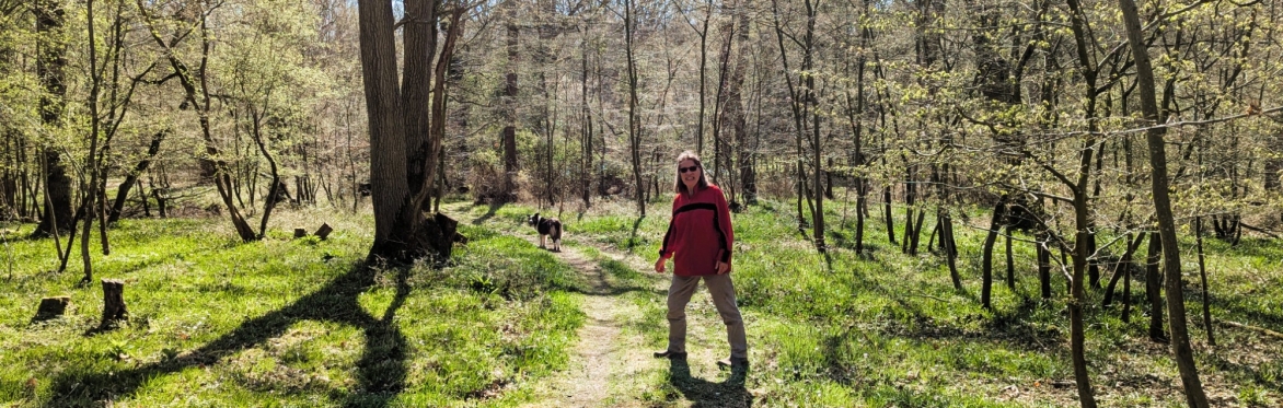 Saltmarsh Coast Walking Festival Winter Walks 2025 - Maureen Bissell featured with dog walking through her private wood. Credit @ Chris Harvey