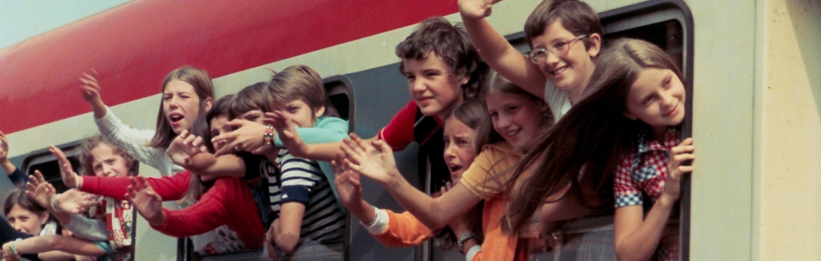 Children waving from a train window.