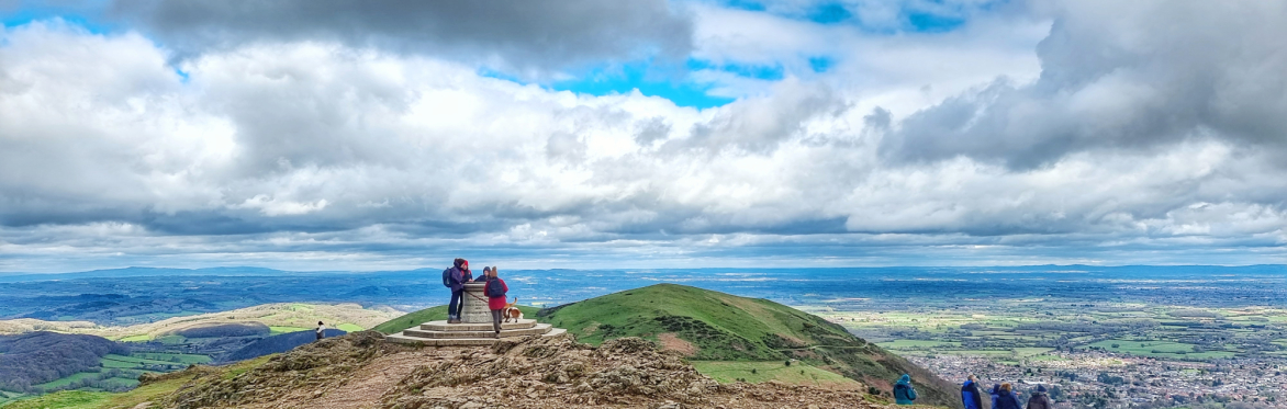 People stand at Worcestershire Beacon, with epic views of several counties beyond