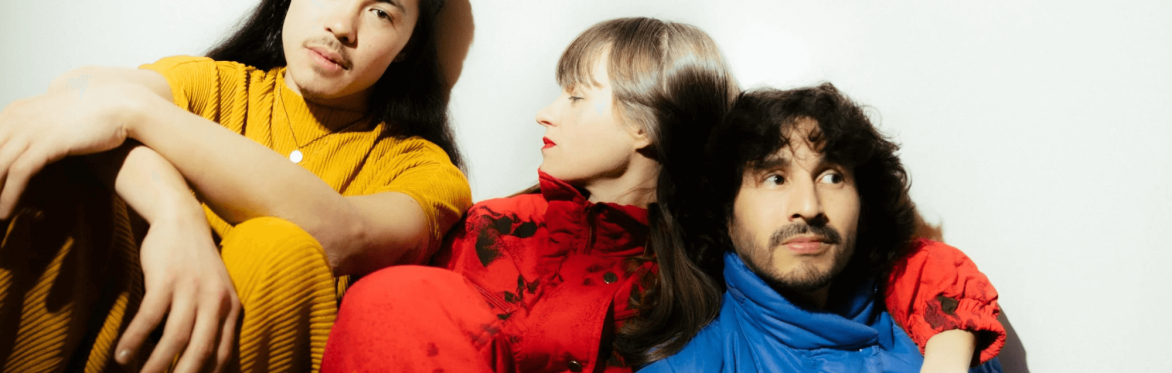 Adele Fournet, Felipe Wurst, and Jordan Auber pose in yellow, red, and blue retro shirts.