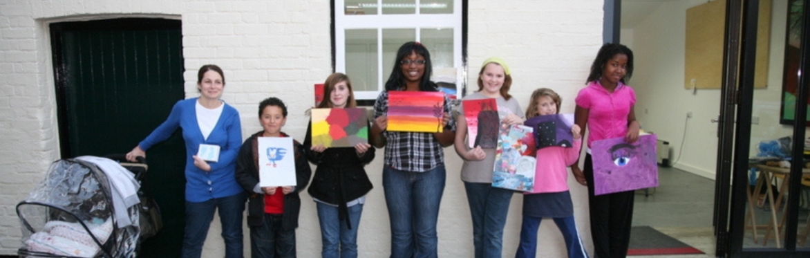 Children and their parents show off artwork outside The Project Space
