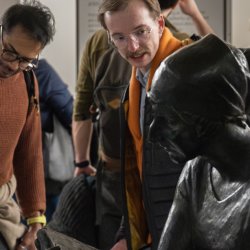People stood in a museum looking at two bronze sculptures on a white plinth.