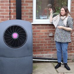 Woman stood next to a house with a heat pump